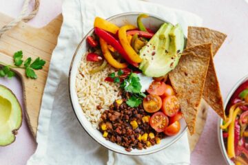 Een afbeelding van een tacobowl met onder andere bonen en avocado.
