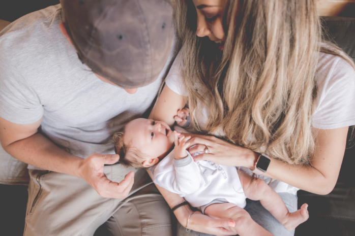 Jonge ouders kijken samen liefdevol naar newborn en downloaden de gratis 24baby app