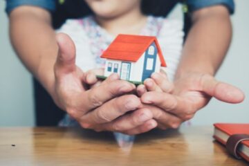 meisje en vader houden symbolisch een houten huisje vast omdat Veilig Thuis betrokken is in het gezin