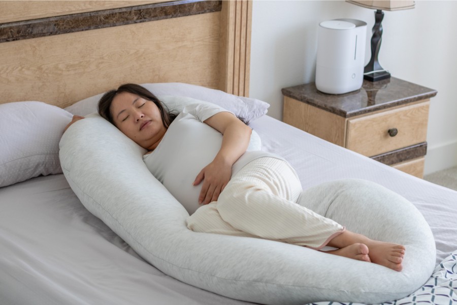 Zwangere vrouw ligt heerlijk op bed met het beste voedingskussen