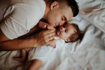 Vader knuffelt zijn baby op bed tijdens de ochtendroutine