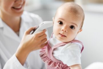 De temperatuur van een baby wordt opgemeten met een oorthermometer