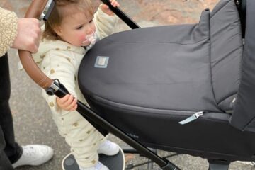 Peuter op meerijdplankje bij kinderwagen