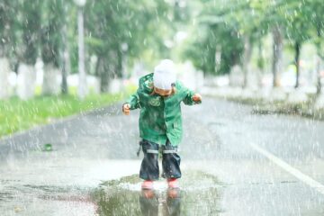 Kindje springt in grote plas met een buitenspeelpak aan