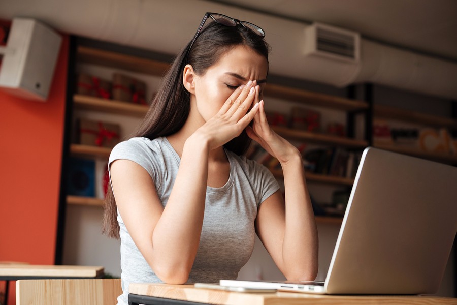 vrouw zit op het werk en heeft last van zwangerschapssymptomen
