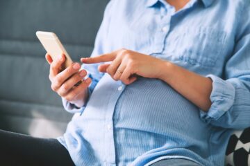 vrouw bekijkt checklist zwangerschap op haar telefoon