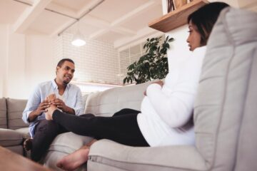 Zwangere vrouw heeft kramp in haar kuit en man masseert haar voeten