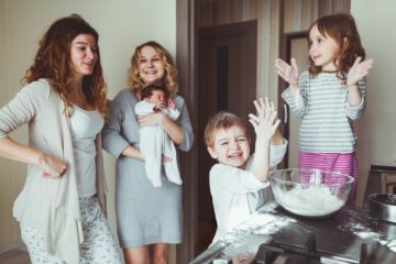 Twee moeder, een baby en twee peuters bakken gezonde Sinterklaas lekkernijen