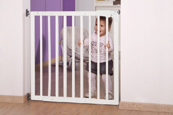 Een peuter blijft in de kamer door een deurhek