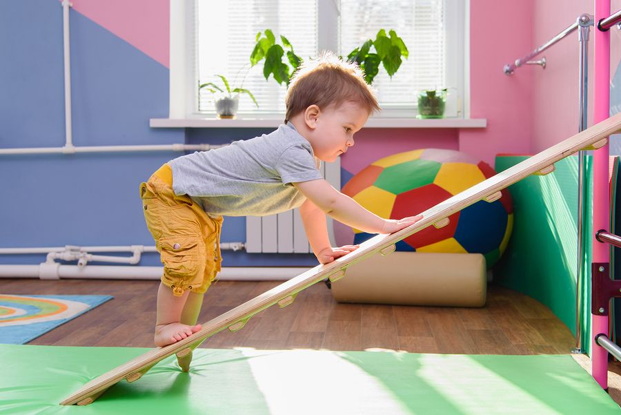 peuter doet aan peutergym en klimt op houten plank