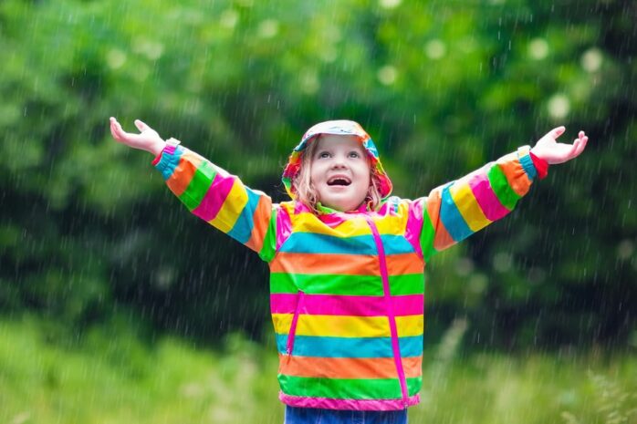 Meisje is aan het buitenspelen en danst in de regen