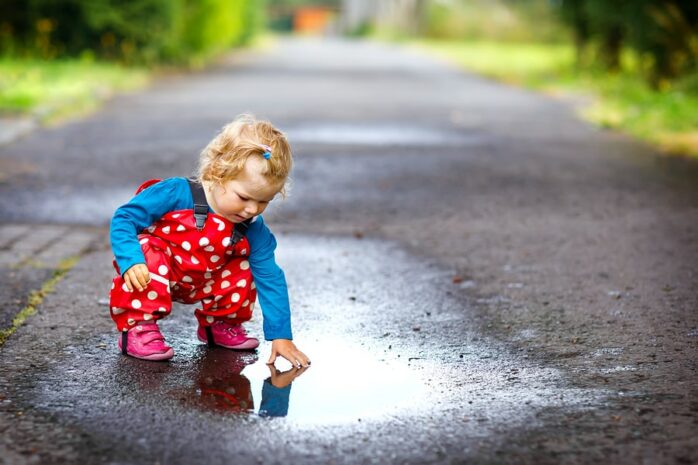 Peuter is aan het buitenspelen en verft met regen en modder