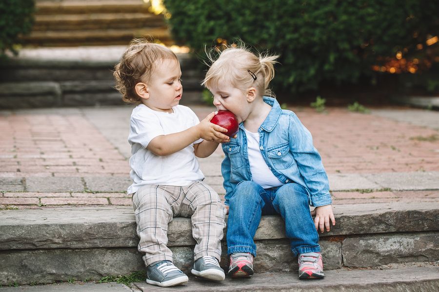 twee peuters leren delen door appel samen te eten