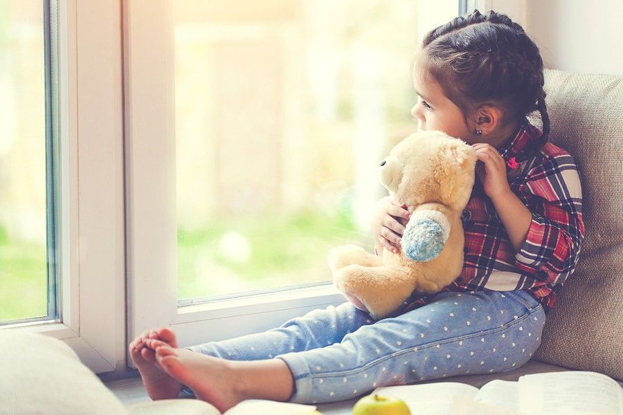 Peutermeisje kijkt verdrietig naar buiten na het scheiden van haar ouders
