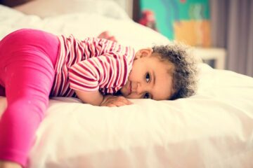 Verlegen peuter ligt op bed