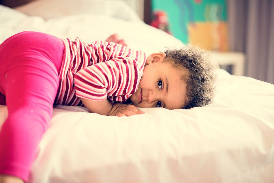 Verlegen peuter ligt op bed