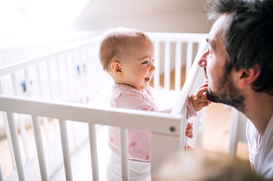 Meisje is vroeg wakker en raakt papa's baard aan vanuit haar bedje