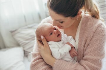Moeder knuffelt haar baby met een wijnvlek