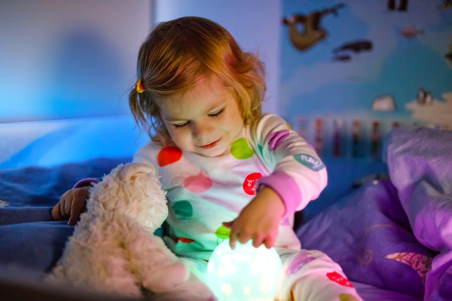 Kindje speelt met nachtlampje die als slaaptrainer gebruikt wordt