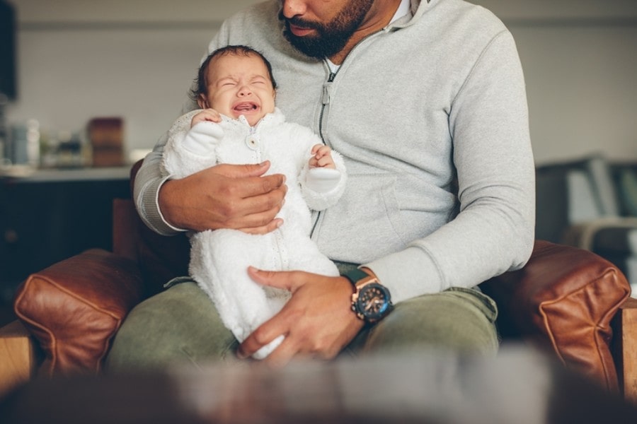 Baby huilt met eerste tranen en zit bij vader op schoot