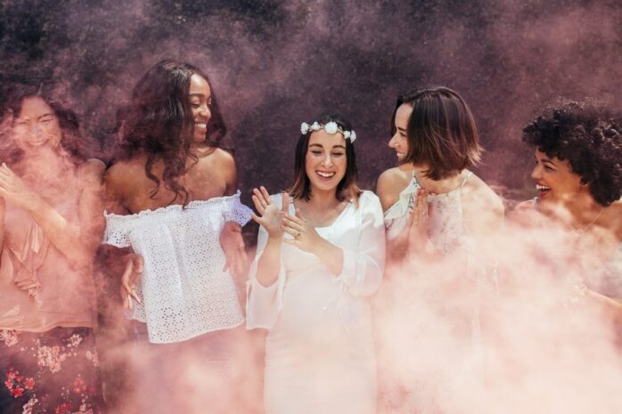 Vrouwen op een gender reveal party met roze rook