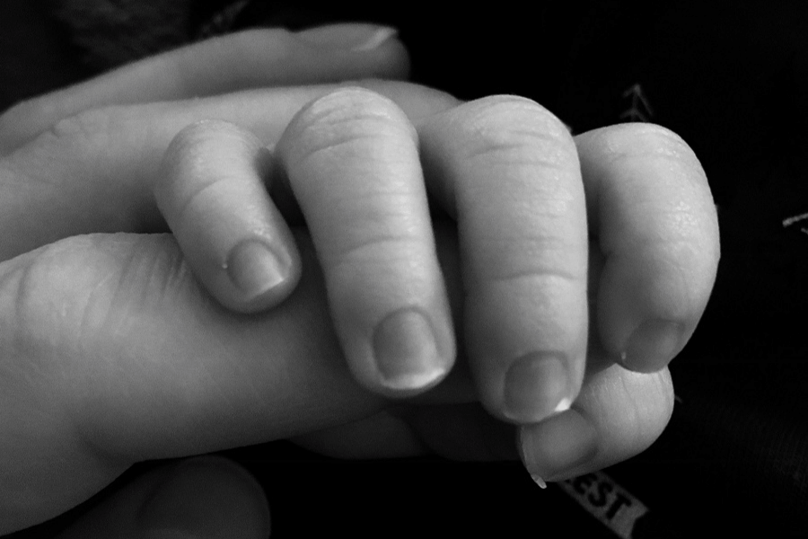 Moeder houdt handje van pasgeboren baby vast als onderdeel van haar bevallingsverhaal