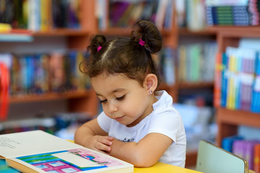 Meisje leest een boekje op het kinderdagverblijf