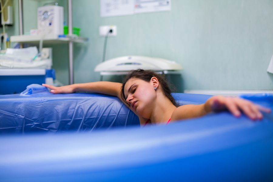 Vrouw ligt in bad te bevallen