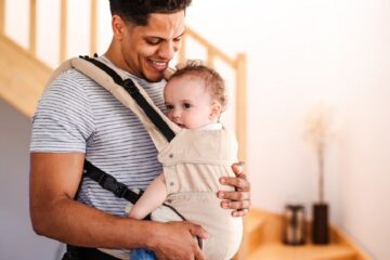 Vader kijkt liefdevol naar zijn baby in de draagzak