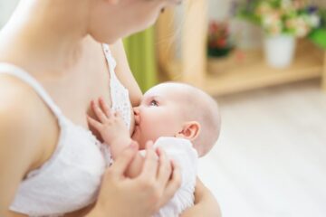 Moeder geeft haar baby borstvoeding met behulp van een witte kanten voedingsbh