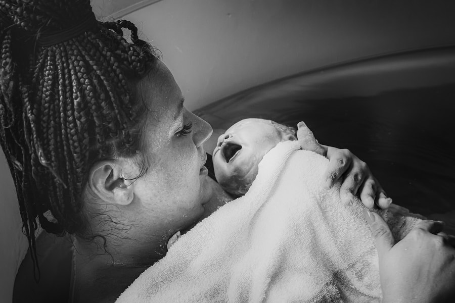 Vrouw is thuis bevallen en houdt pasgeboren baby vast