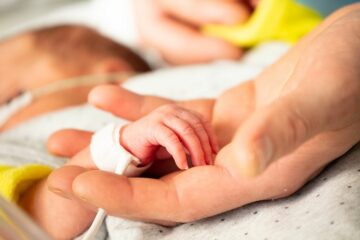 Close up van moeder die hand van haar baby vasthoudt op de neonatologie afdeling