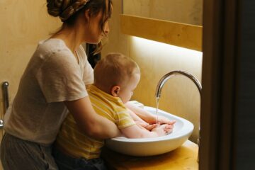 Moeder en peuter zijn samen hun handen aan het wassen om besmetting met coronavirus te voorkomen