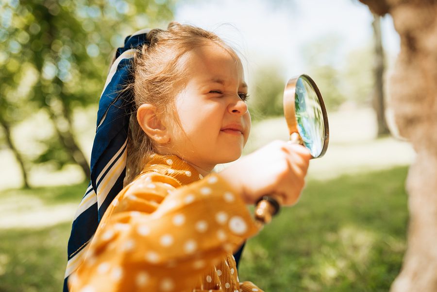 Peuter is bezig met tuinspelletjes en kijkt door een vergrootglas