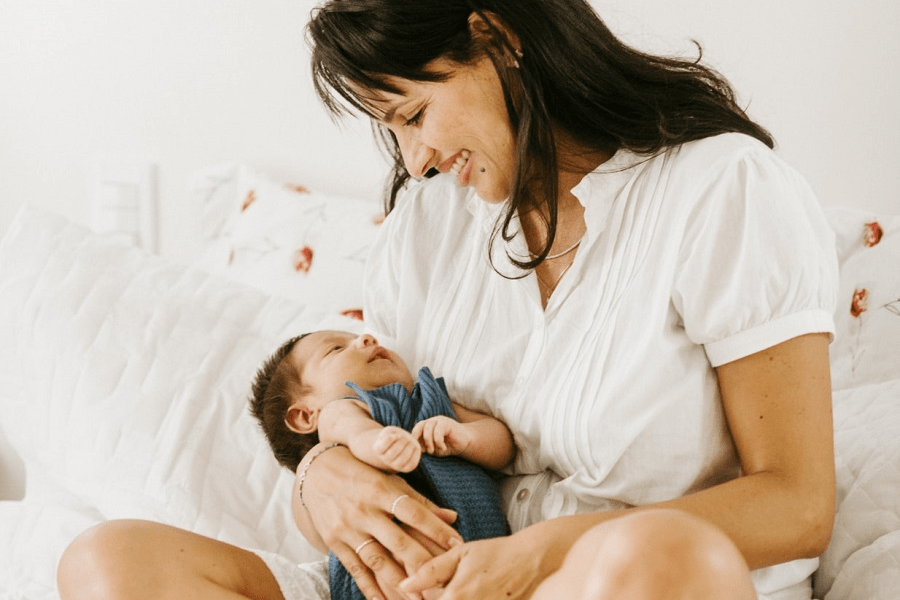 Moeder houdt haar baby vast en vraagt zich af of de vaccinaties nog doorgaan door de corona-uitbraak