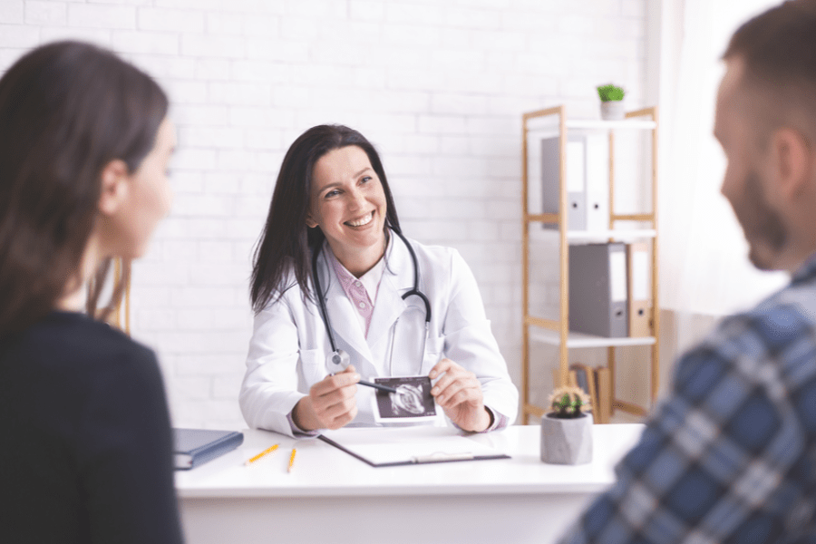 afspraken verloskundige tijdens de zwangerschap: een zwanger stel zit tegenover de verloskundige