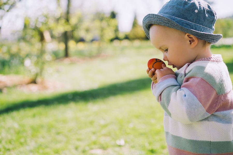Kindje ruikt aan paasei terwijl hij paasspelletjes speelt