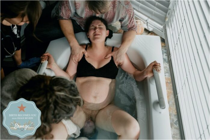 Vrouw perst in bad en het hoofdje van de baby steekt al uit haar vagina