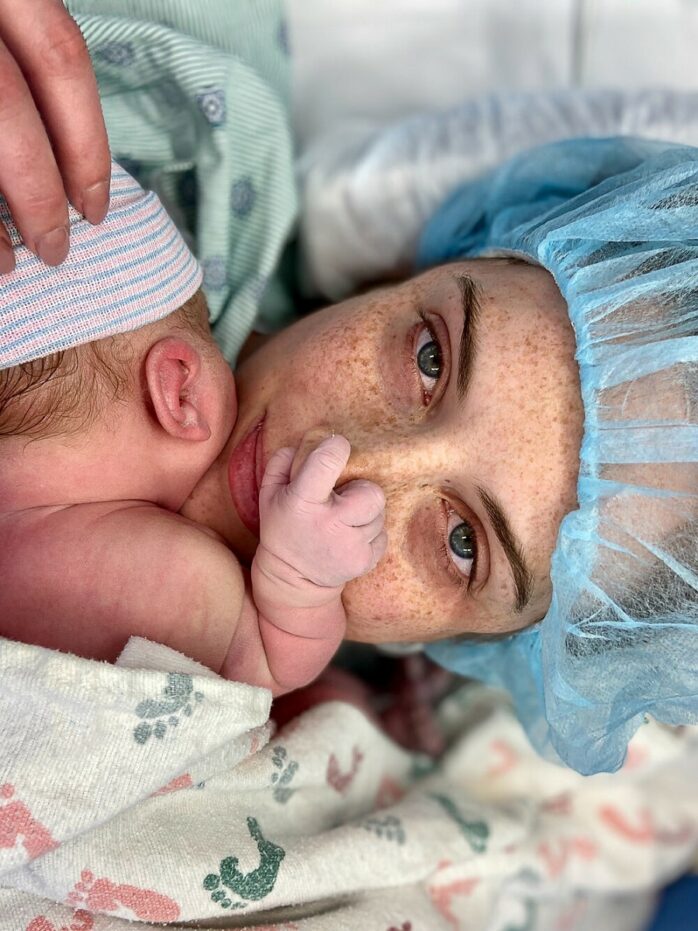 Pasgeboren baby ligt bij moeder en houdt haar neus vast