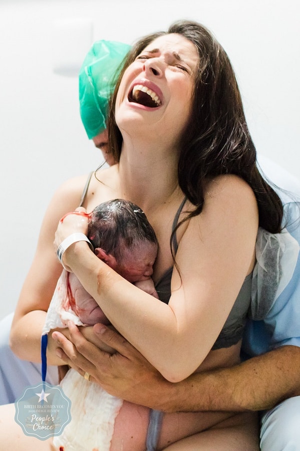 Pas bevallen vrouw houdt geëmotioneerd haar pasgeboren baby vast