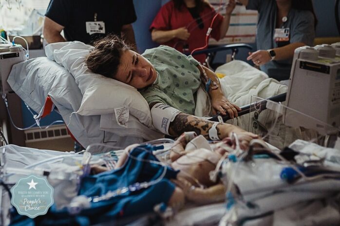 Net bevallen vrouw kijkt huilend naar haar baby