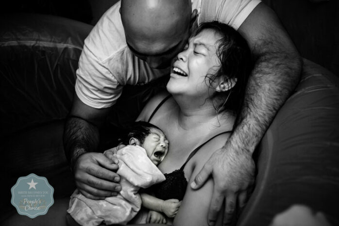 Man houdt zijn pas bevallen vrouw vast, die haar baby huilend vasthoudt