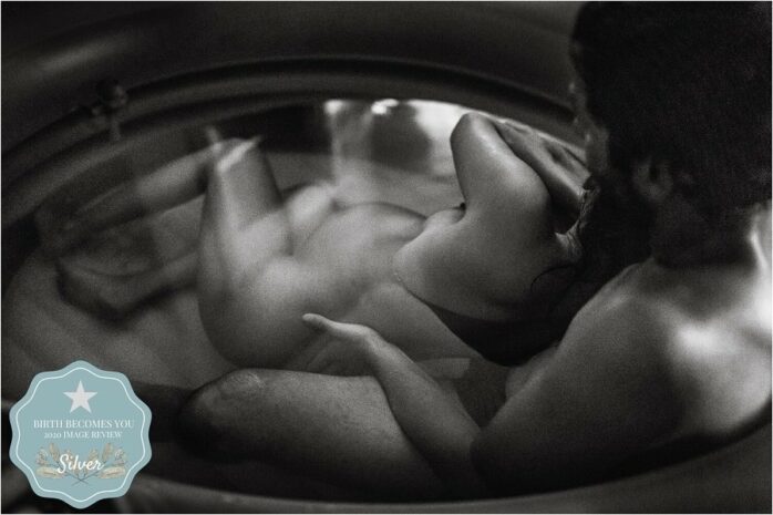 Man ondersteunt zijn vrouw tijdens een badbevalling