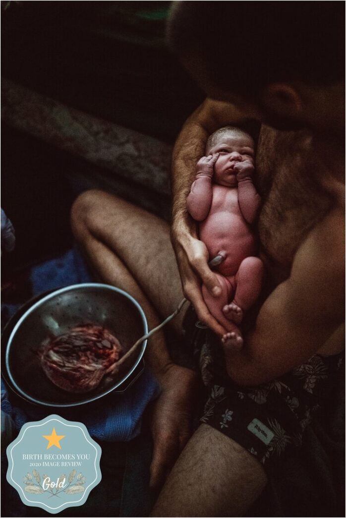 Vader houdt pasgeboren baby vast die nog aan placenta vast zit