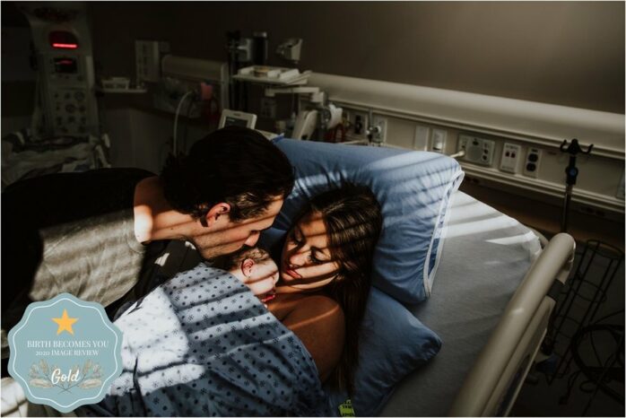 Moeder, vader en pasgeboren baby liggen vredig in ziekenhuiskamer