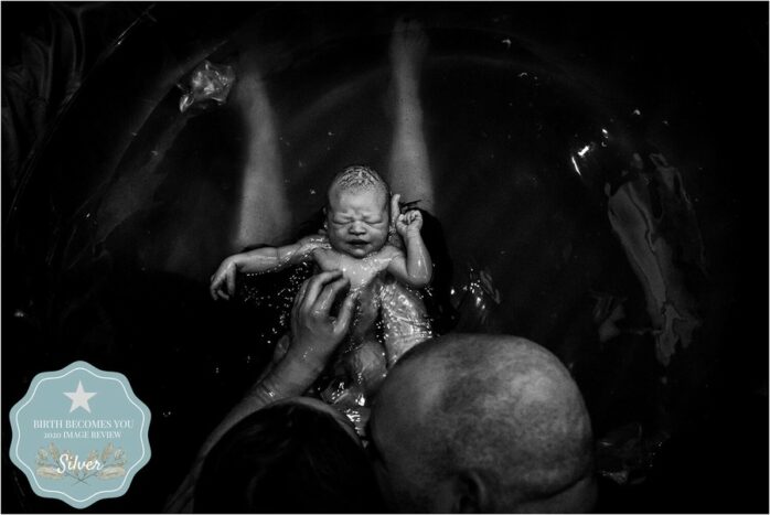 Vader en moeder in bad bekijken hun pasgeboren baby