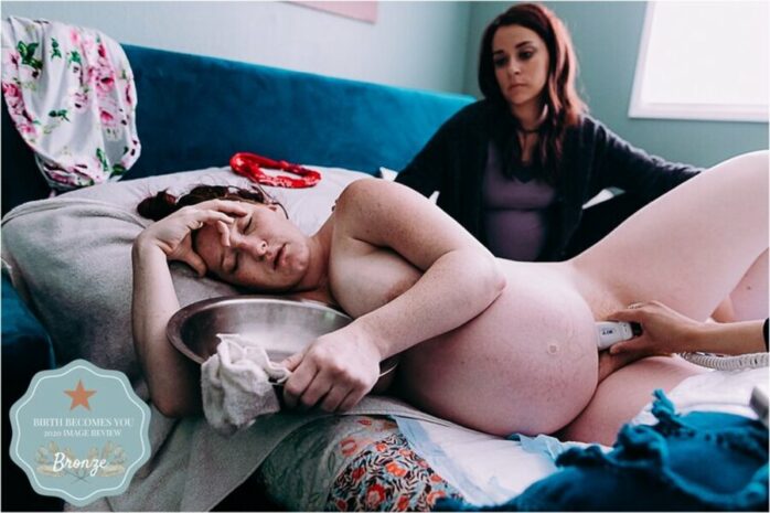 Vrouw zit naast haar vrouw tijdens de bevalling