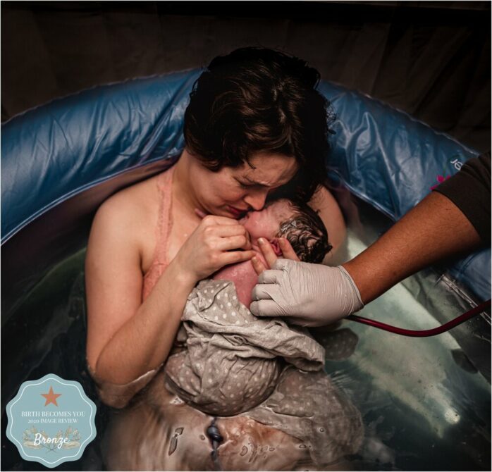 Moeder kust zacht en huilend haar pasgeboren baby na badbevalling