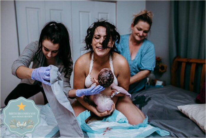 Moeder neemt pasgeboren baby aan op haar knieeën