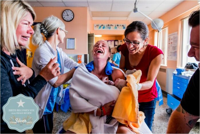 Moeder lacht en huilt tegelijk na de geboorte van haar baby